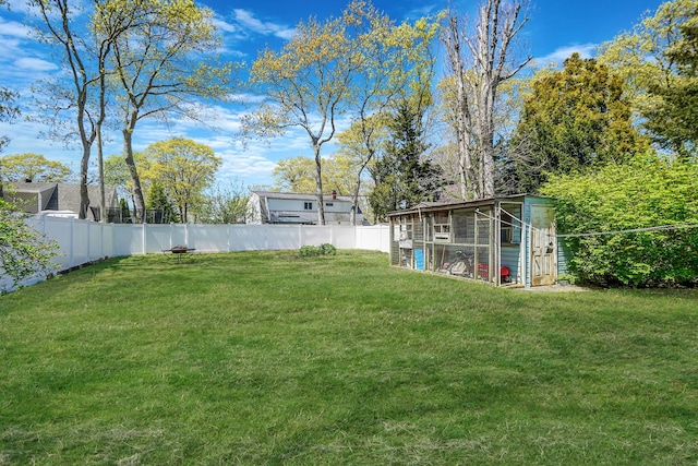 view of yard with a fenced backyard, exterior structure, and an outbuilding