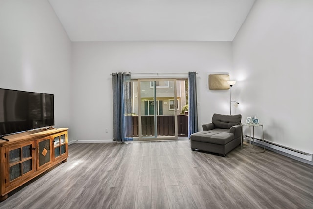 living area with baseboards, a baseboard heating unit, wood finished floors, and lofted ceiling