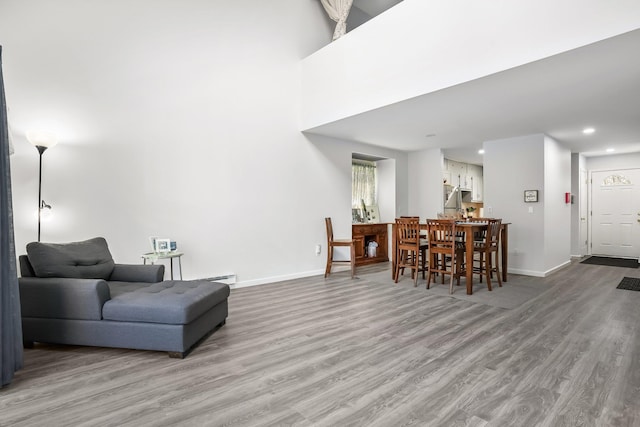 living room featuring baseboards, baseboard heating, recessed lighting, and wood finished floors