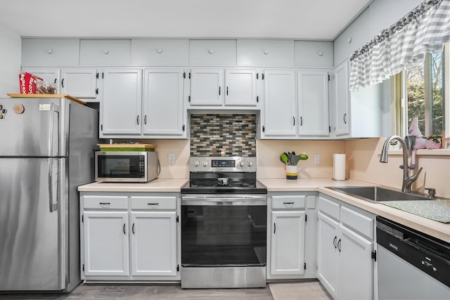 kitchen with a sink, white cabinetry, appliances with stainless steel finishes, and light countertops