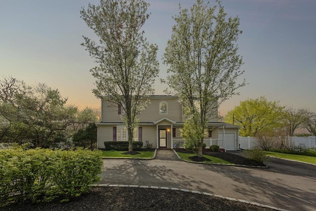view of front of home featuring fence, covered porch, a garage, and aphalt driveway