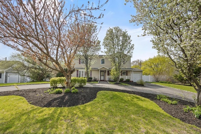 view of front of home featuring fence, curved driveway, and a front lawn