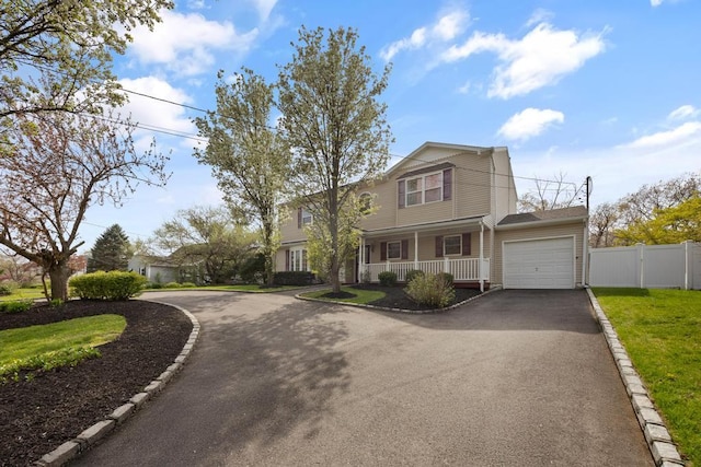 view of front facade with a porch, driveway, a garage, fence, and a front lawn