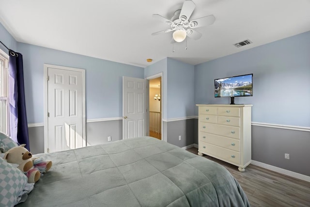 bedroom featuring visible vents, a ceiling fan, baseboards, and wood finished floors