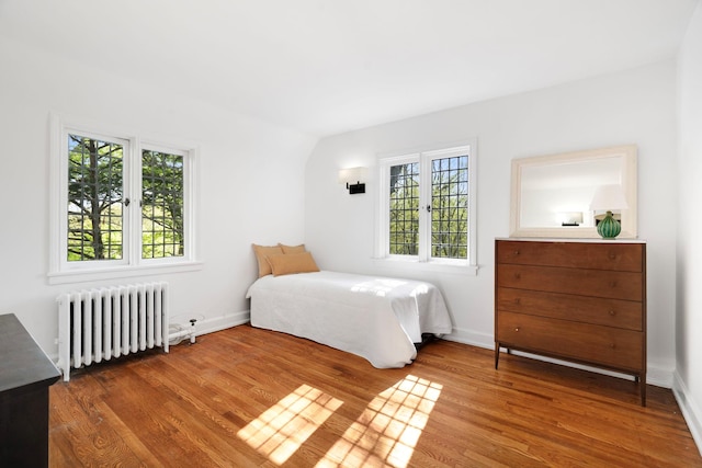 bedroom with wood finished floors, baseboards, and radiator heating unit