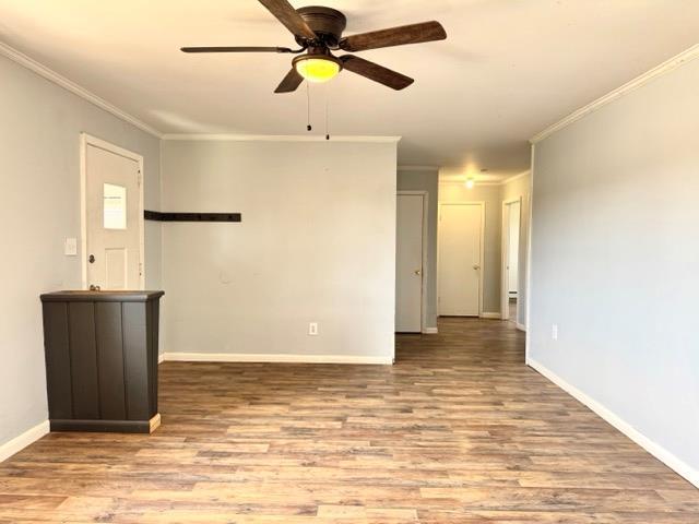 empty room featuring baseboards, ceiling fan, ornamental molding, and wood finished floors