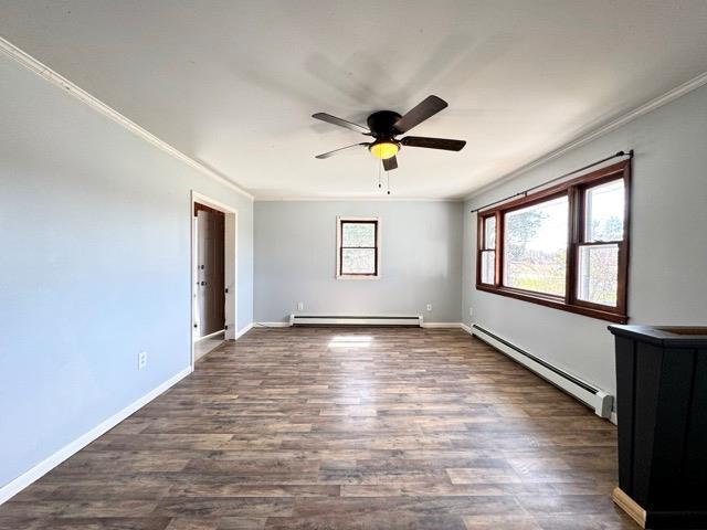 unfurnished room featuring dark wood-style flooring, ceiling fan, ornamental molding, and a baseboard radiator