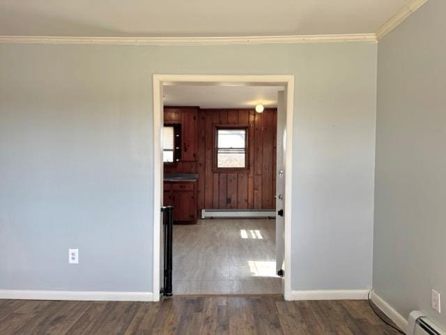 interior space with baseboard heating, baseboards, wood finished floors, a baseboard radiator, and ornamental molding