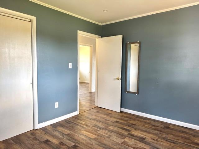 unfurnished bedroom with baseboards, ornamental molding, and wood finished floors