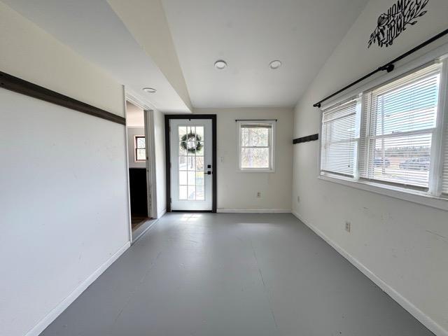 foyer with baseboards, concrete floors, and lofted ceiling