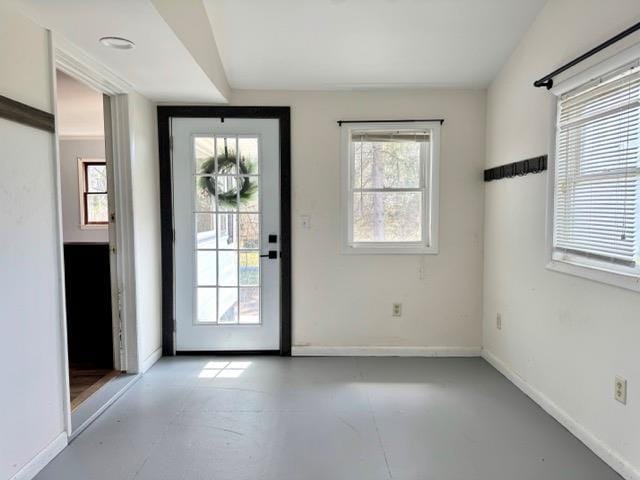 doorway featuring baseboards and concrete flooring