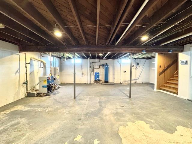 unfinished basement featuring stairway and water heater