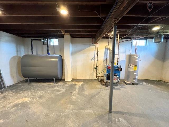 basement with a heating unit, heating fuel, water heater, and a healthy amount of sunlight