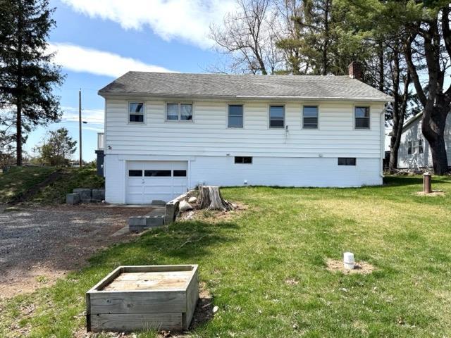 exterior space with an attached garage, driveway, a yard, and a chimney