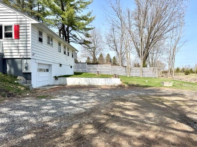 view of home's exterior featuring an attached garage, fence, and driveway