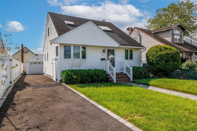 bungalow featuring a detached garage, fence, driveway, and an outdoor structure