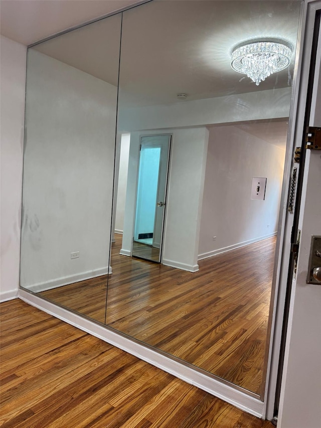 unfurnished room with baseboards, a chandelier, and wood finished floors