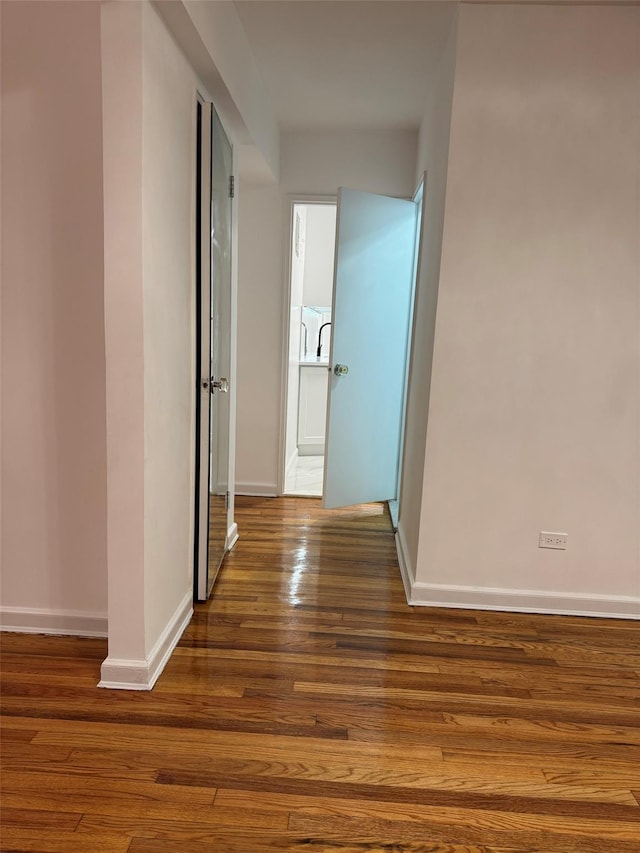 corridor with baseboards and wood finished floors