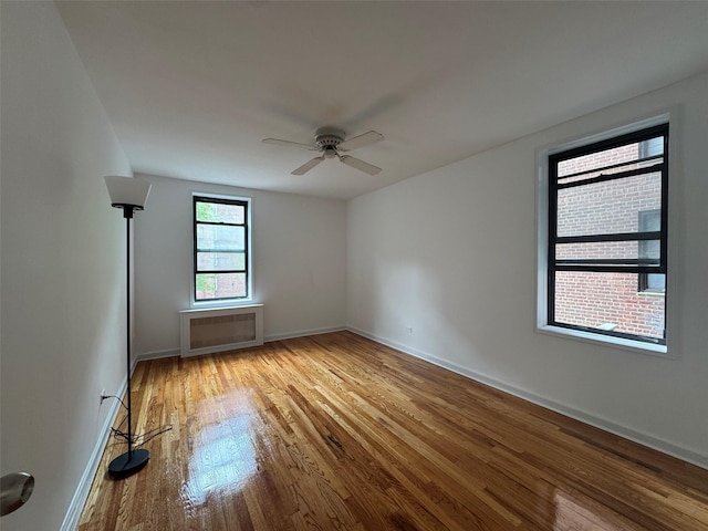 spare room featuring baseboards, ceiling fan, and wood finished floors