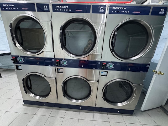 community laundry room with tile patterned floors and stacked washer / drying machine