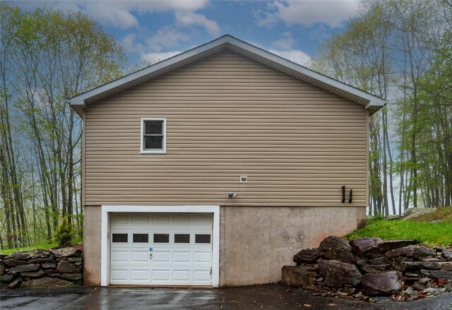 view of home's exterior with an attached garage and asphalt driveway