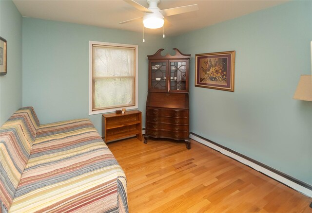 bedroom featuring a baseboard heating unit, light wood finished floors, and a ceiling fan