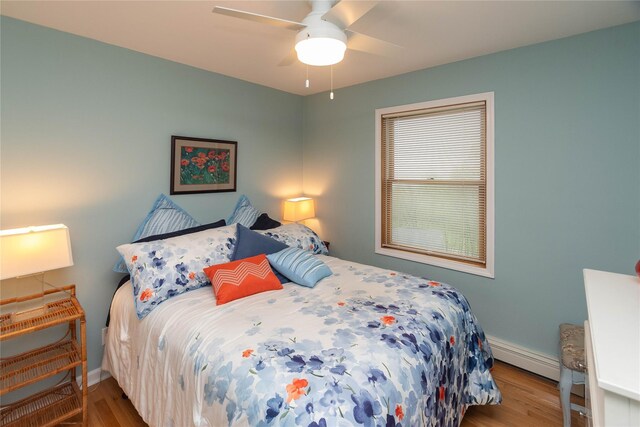 bedroom with wood finished floors, baseboards, a baseboard heating unit, and a ceiling fan