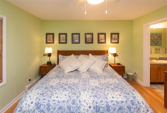 bedroom with light wood-style flooring, a sink, baseboards, ensuite bathroom, and a ceiling fan