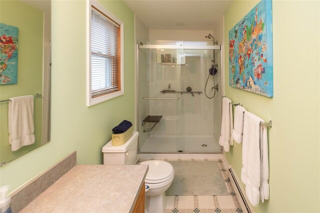 bathroom with a baseboard heating unit, a stall shower, toilet, vanity, and tile patterned floors