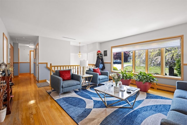 living room featuring attic access, wood finished floors, and a baseboard radiator