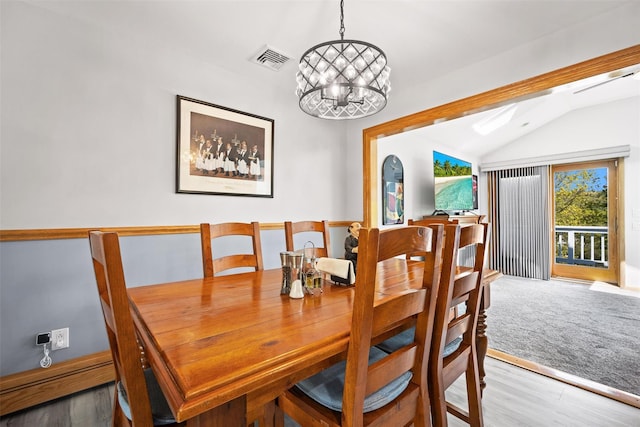 dining room featuring visible vents, wood finished floors, lofted ceiling, and a notable chandelier