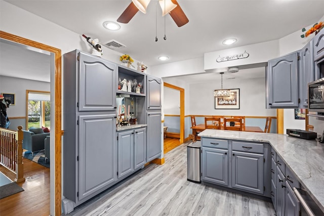 kitchen with gray cabinetry, visible vents, and ceiling fan with notable chandelier