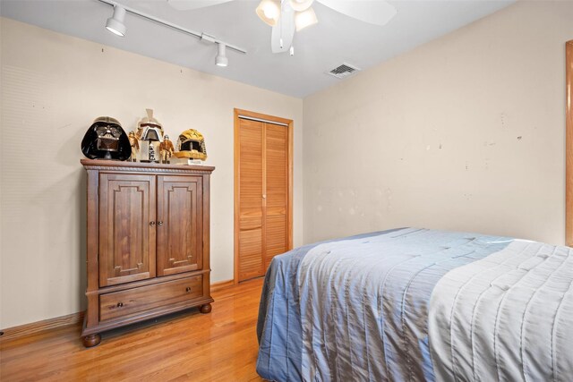 bedroom featuring a closet, rail lighting, light wood-type flooring, visible vents, and ceiling fan