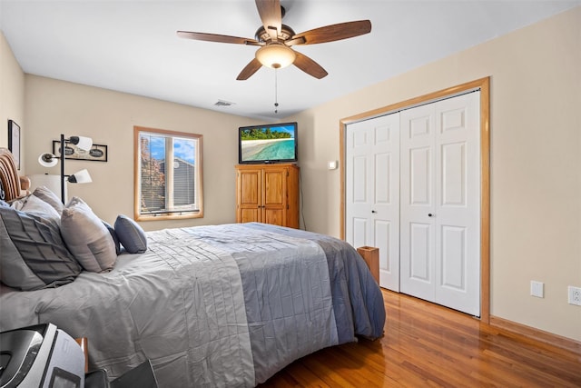 bedroom with a closet, baseboards, ceiling fan, visible vents, and wood finished floors