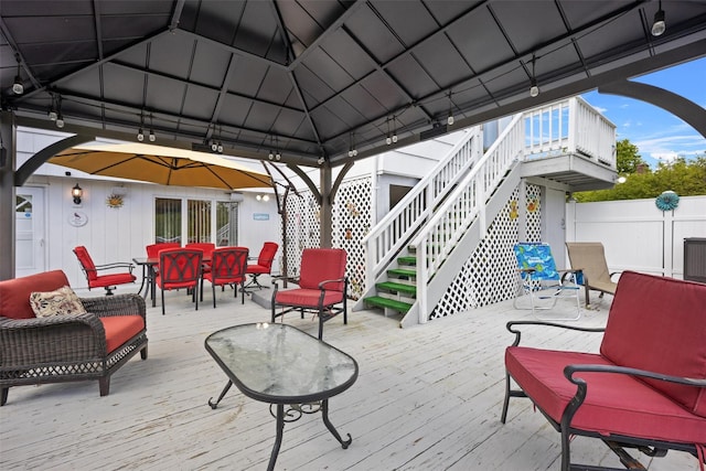deck featuring fence, stairway, a gazebo, and outdoor dining space