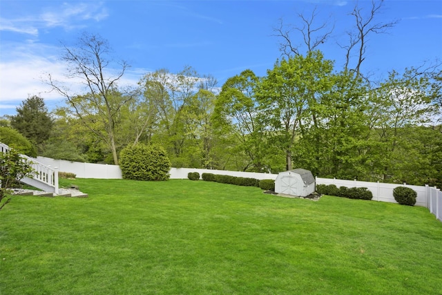 view of yard featuring an outbuilding, a fenced backyard, and a storage unit