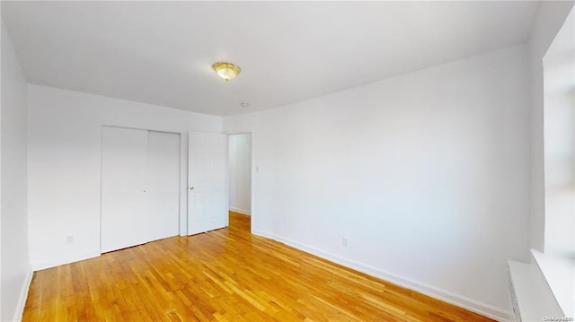 unfurnished bedroom featuring light wood-style floors, baseboards, and a closet