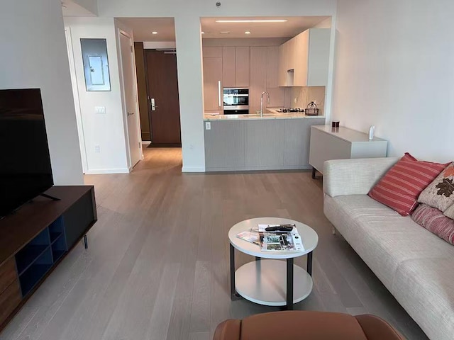 living room with recessed lighting, baseboards, and light wood-style flooring
