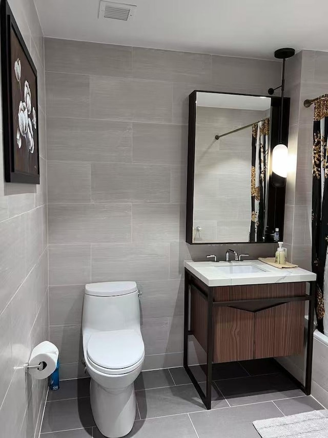 full bathroom featuring vanity, toilet, tile patterned floors, tile walls, and visible vents