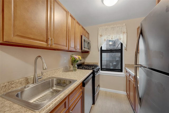 kitchen featuring a sink, stainless steel appliances, light wood-type flooring, light countertops, and baseboards