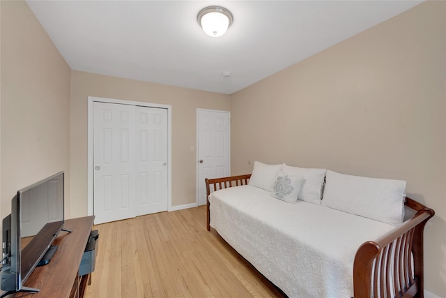 bedroom with a closet, light wood-type flooring, and baseboards