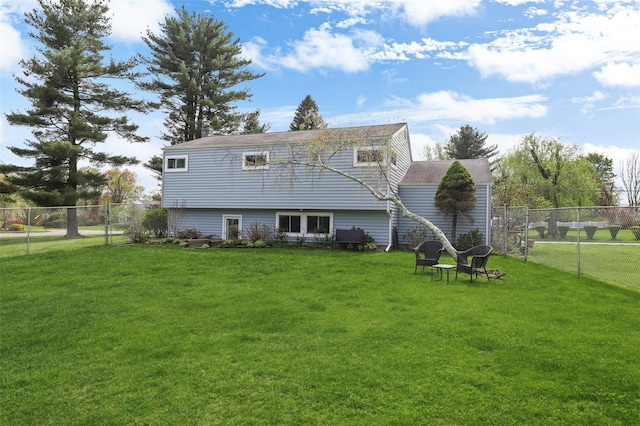 rear view of house featuring fence and a lawn