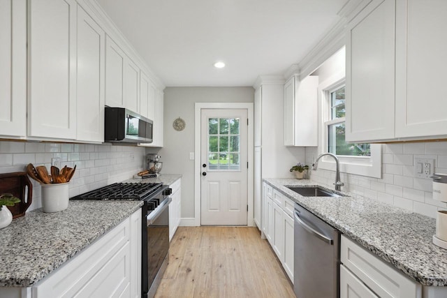 kitchen with light wood-style flooring, a sink, stainless steel appliances, white cabinets, and recessed lighting