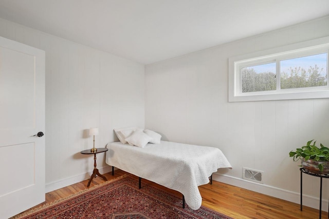bedroom with visible vents, wood finished floors, and baseboards