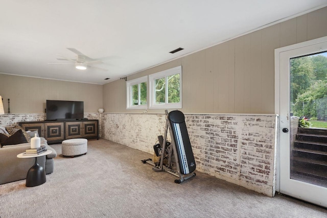 living area featuring visible vents, wooden walls, ceiling fan, and carpet floors