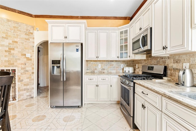142 Primrose Ave, Mount Vernon, NY 10552 - kitchen with crown molding, light stone countertops, appliances with stainless steel finishes, arched walkways, and backsplash