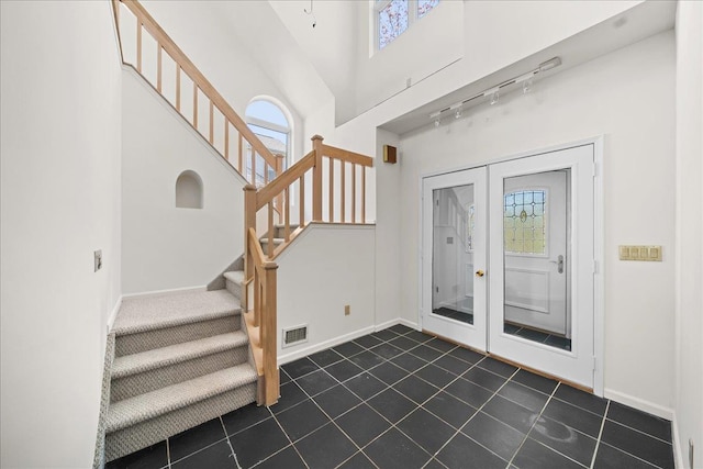 entrance foyer with track lighting, visible vents, baseboards, stairway, and dark tile patterned floors
