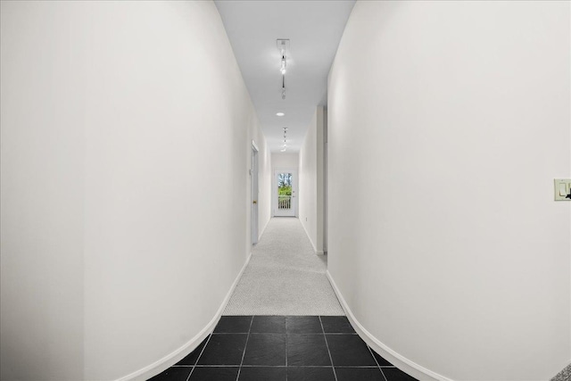 hallway with dark tile patterned flooring, baseboards, and dark colored carpet