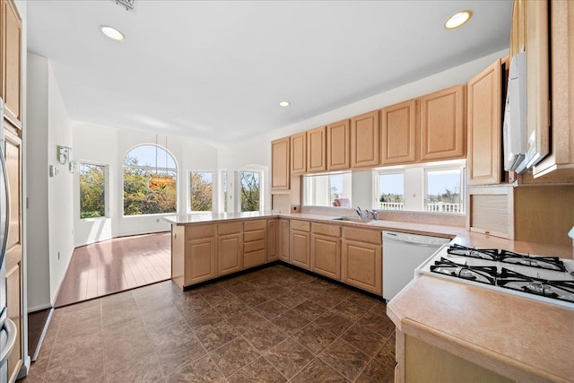 kitchen with a sink, light countertops, light brown cabinets, recessed lighting, and white appliances