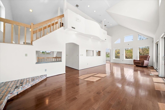 unfurnished living room with visible vents, stairway, high vaulted ceiling, and hardwood / wood-style flooring